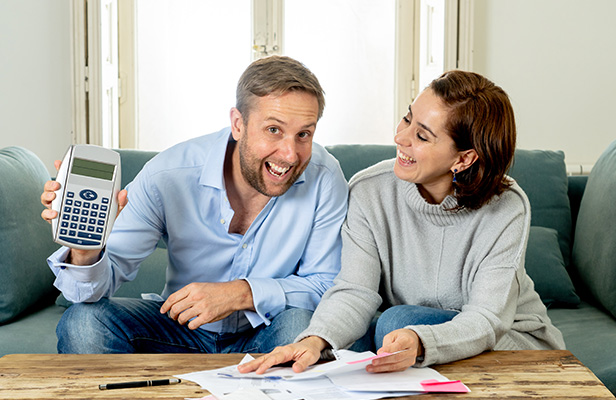 Couple heureux présentant une calculette pour estimer leurs remboursements par la mutuelle MBTP