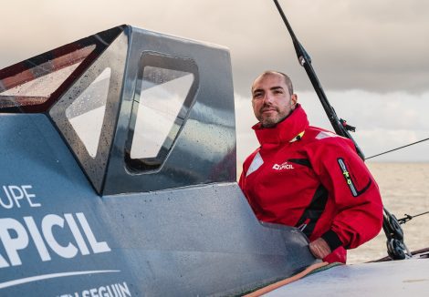 Damien Seguin skipper à bord de son bateau Apicil en train de regarde l'horizon